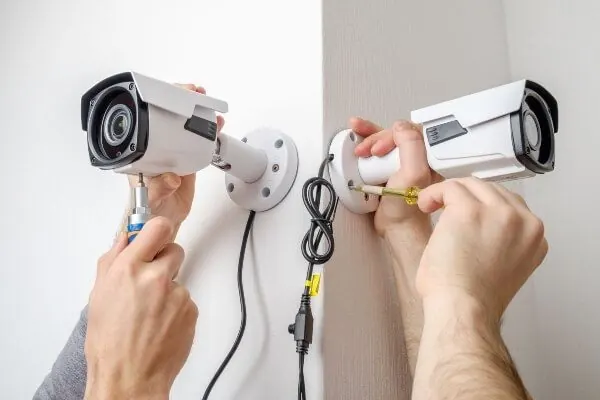 Técnico instalando câmeras de segurança brancas em uma parede